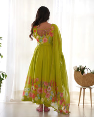 Woman wearing a green floral dress standing in a bright room with sheer curtains.