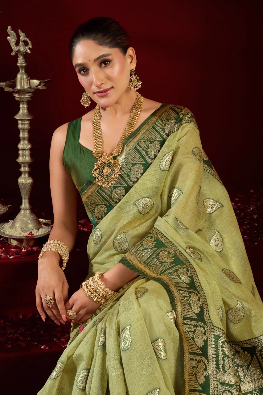 Woman in a green saree with gold embroidery against a dark background