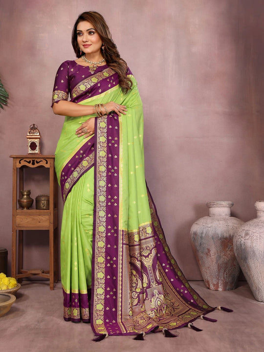Woman wearing a green and purple saree with a neutral background