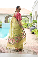 Woman in a yellow saree with floral patterns standing by a poolside.