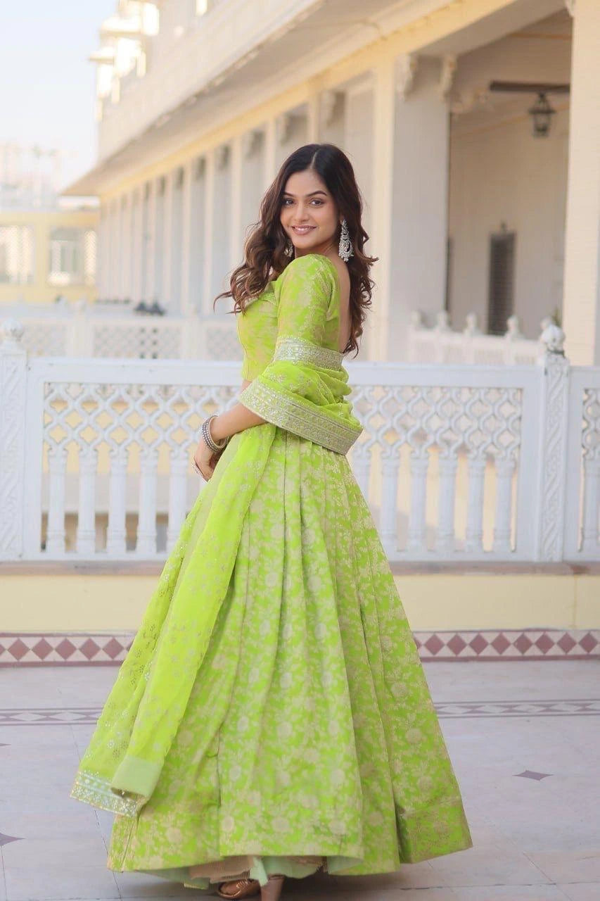 Woman in a bright green traditional outfit standing in front of a white building.