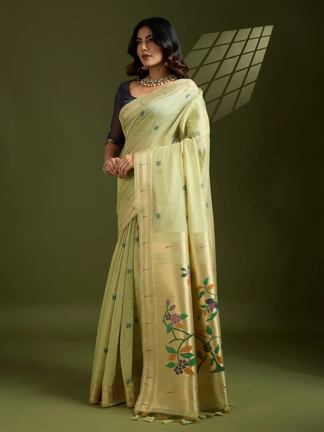 Woman wearing a light green saree with floral patterns on a dark background