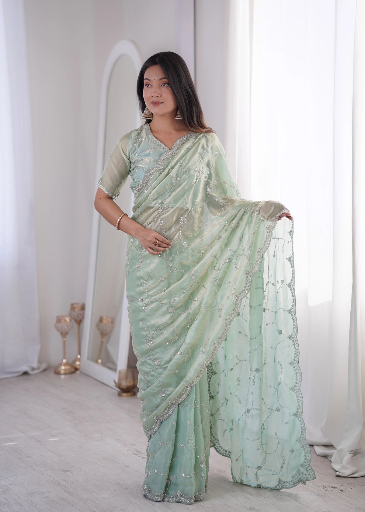Woman wearing a light green saree with a white background