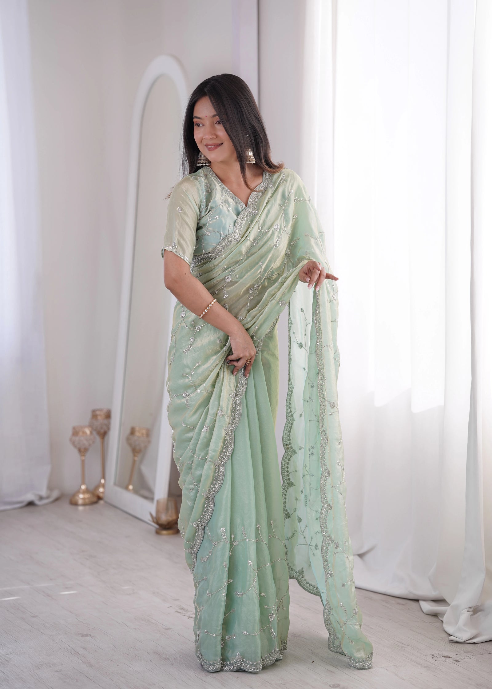 Woman wearing a light green saree with a white background