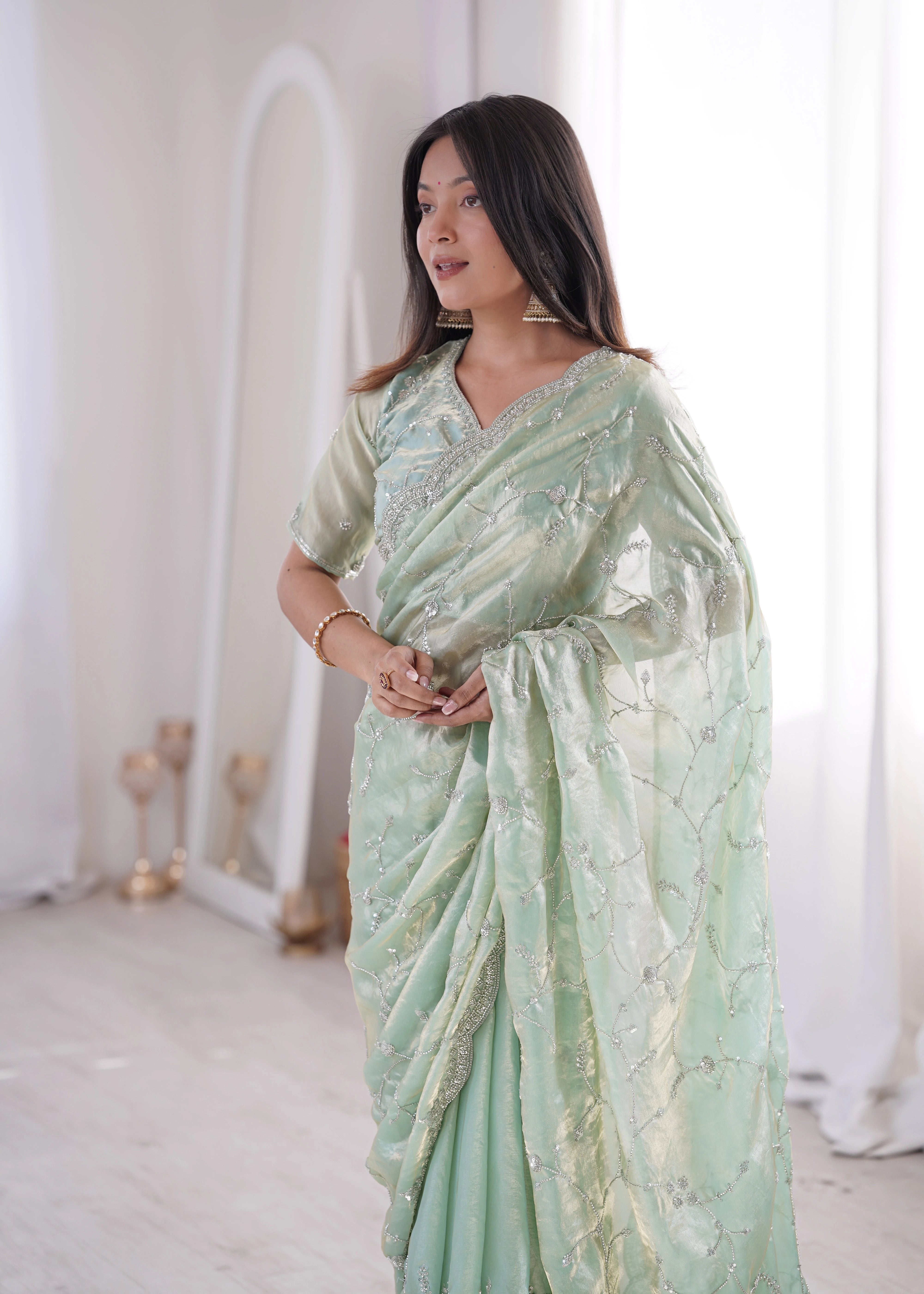 Woman wearing a light green saree with a white background