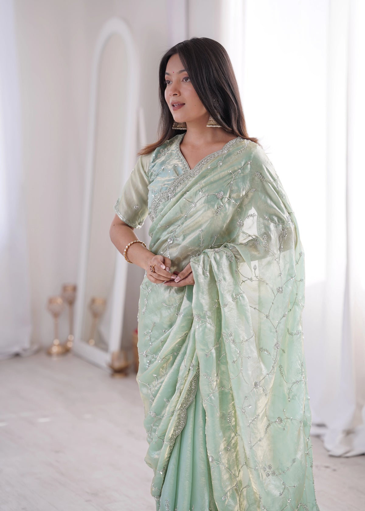 Woman wearing a light green saree with a white background