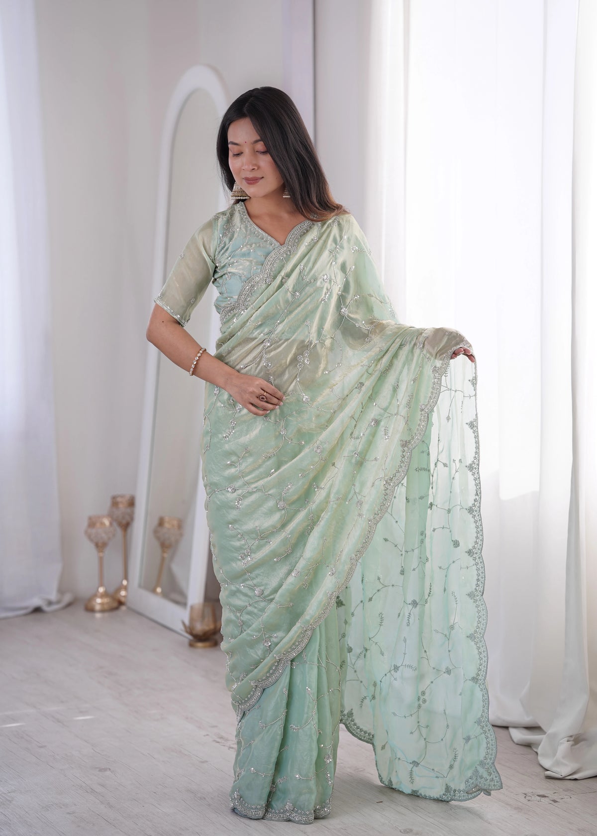 Woman wearing a light green saree with a white background