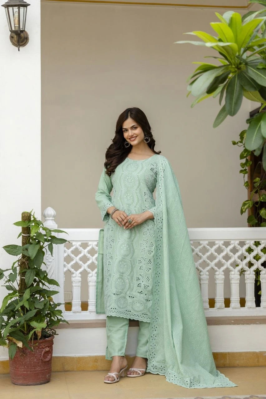 Woman in a light green traditional outfit standing in front of a white railing with plants.