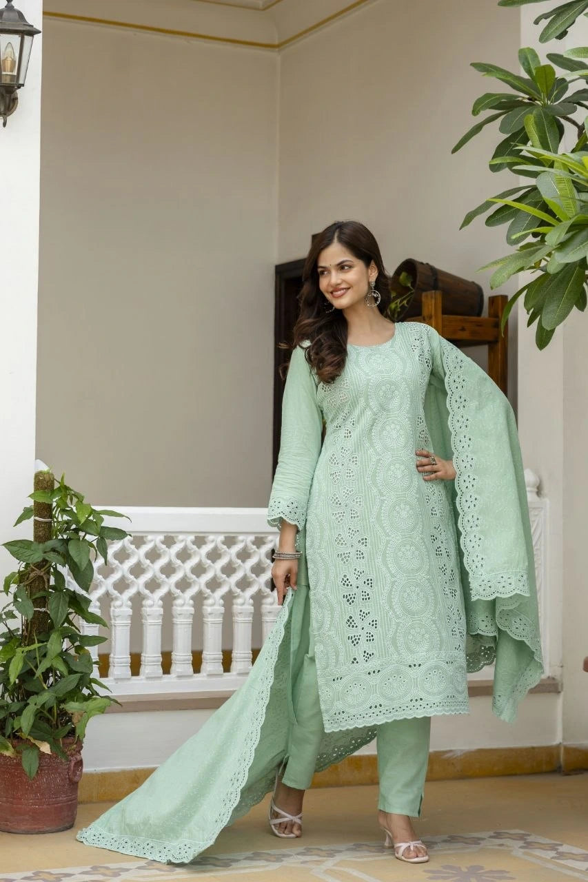 Woman in a light green traditional outfit standing in an indoor setting with plants.