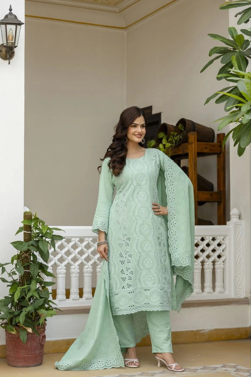 Woman in a light green traditional outfit standing in a decorated indoor setting with plants.