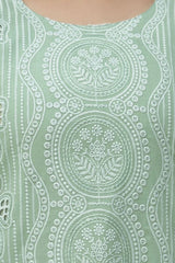 Close-up of a green fabric with intricate white embroidery