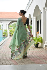 Woman in a light green saree with floral patterns walking near a poolside.