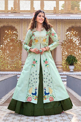 Woman wearing a light green and dark green embroidered traditional outfit in front of an ornate architectural background.