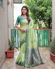 Woman wearing a green saree with a patterned border on a balcony.