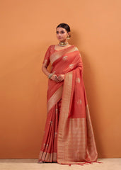 Woman wearing a red saree with gold border against an orange background