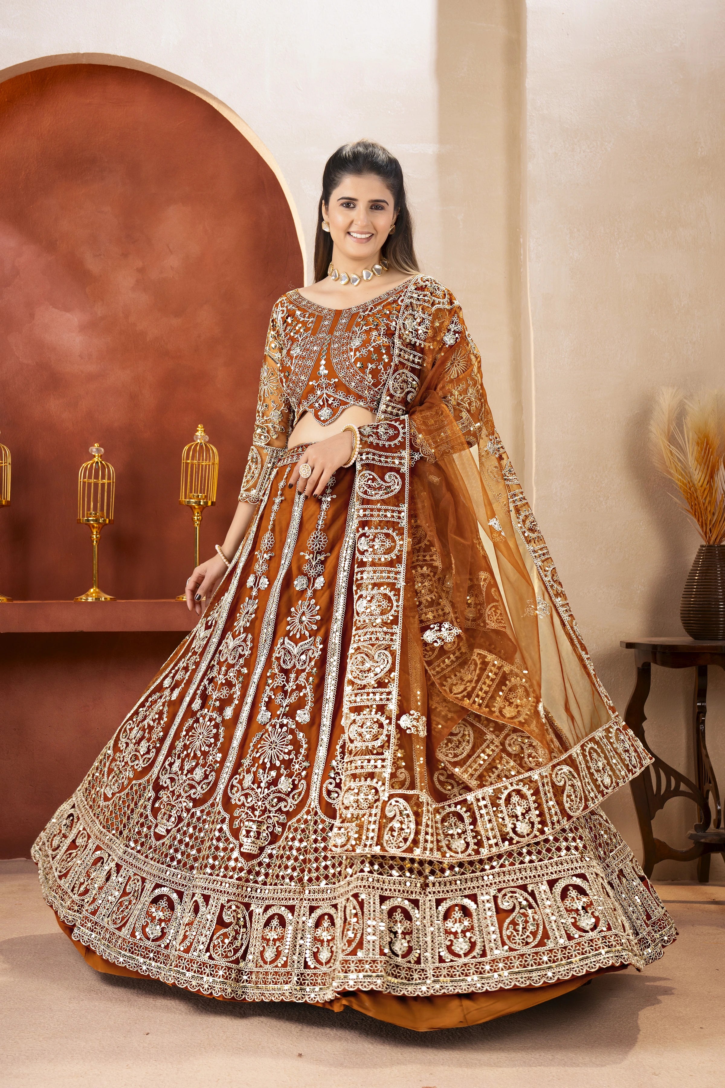 Woman in an ornate traditional outfit with intricate designs in a warm-toned room.