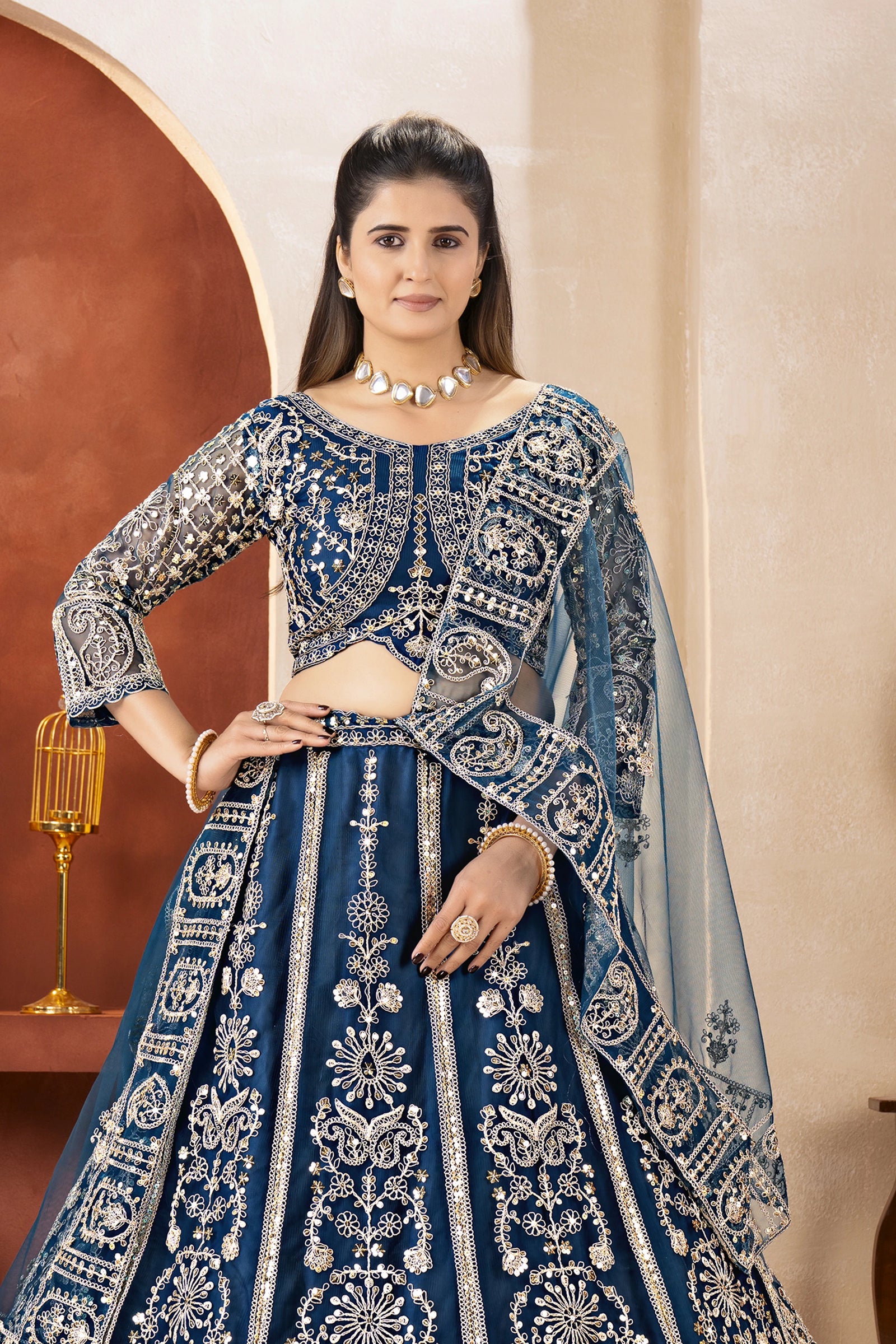 Woman wearing a blue embroidered traditional outfit with a beige background