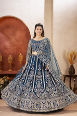 Woman wearing a blue and silver embroidered traditional outfit in a decorated room.