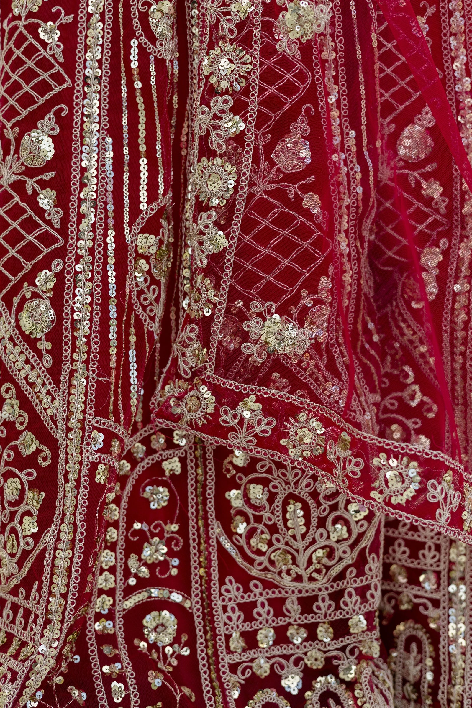 Close-up of a red fabric with intricate gold embroidery and sequin work.