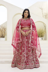 Woman in a red and white embroidered traditional outfit standing on steps with a neutral background