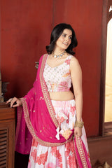 Woman in a traditional outfit with a pink and white saree against a red wall.