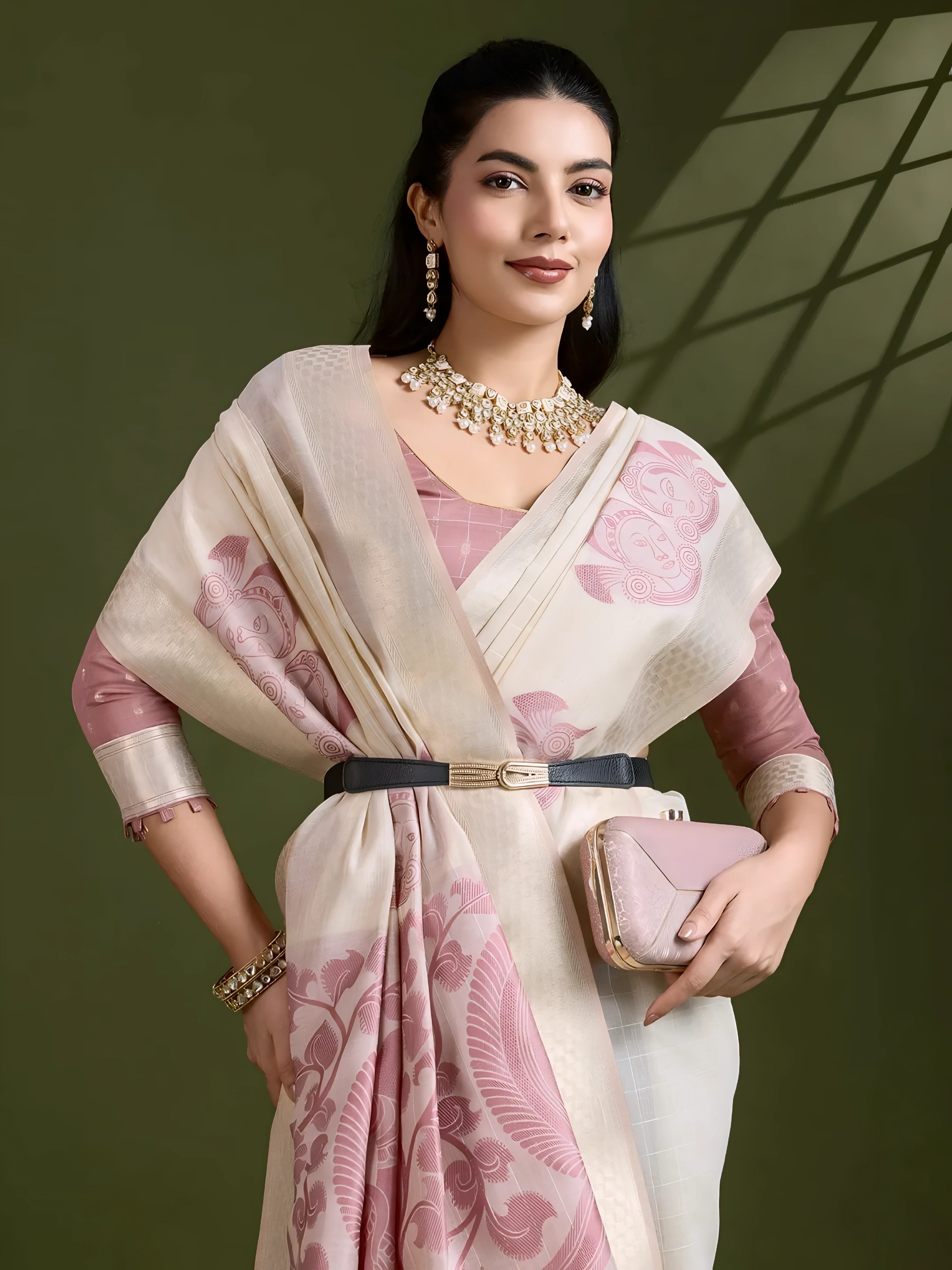 A woman models an elegant Beige Soft Muga Cotton Saree. The saree features large Kalamkari-style prints of peacocks and florals in a contrasting Dusty Rose Pink on the pallu. She wears a dusty pink elbow-sleeve blouse and accessorizes with a gold and pearl Kundan choker necklace, posing indoors.