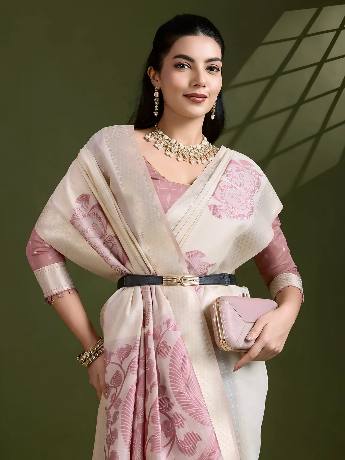 A woman models an elegant Beige Soft Muga Cotton Saree. The saree features large Kalamkari-style prints of peacocks and florals in a contrasting Dusty Rose Pink on the pallu. She wears a dusty pink elbow-sleeve blouse and accessorizes with a gold and pearl Kundan choker necklace, posing indoors.