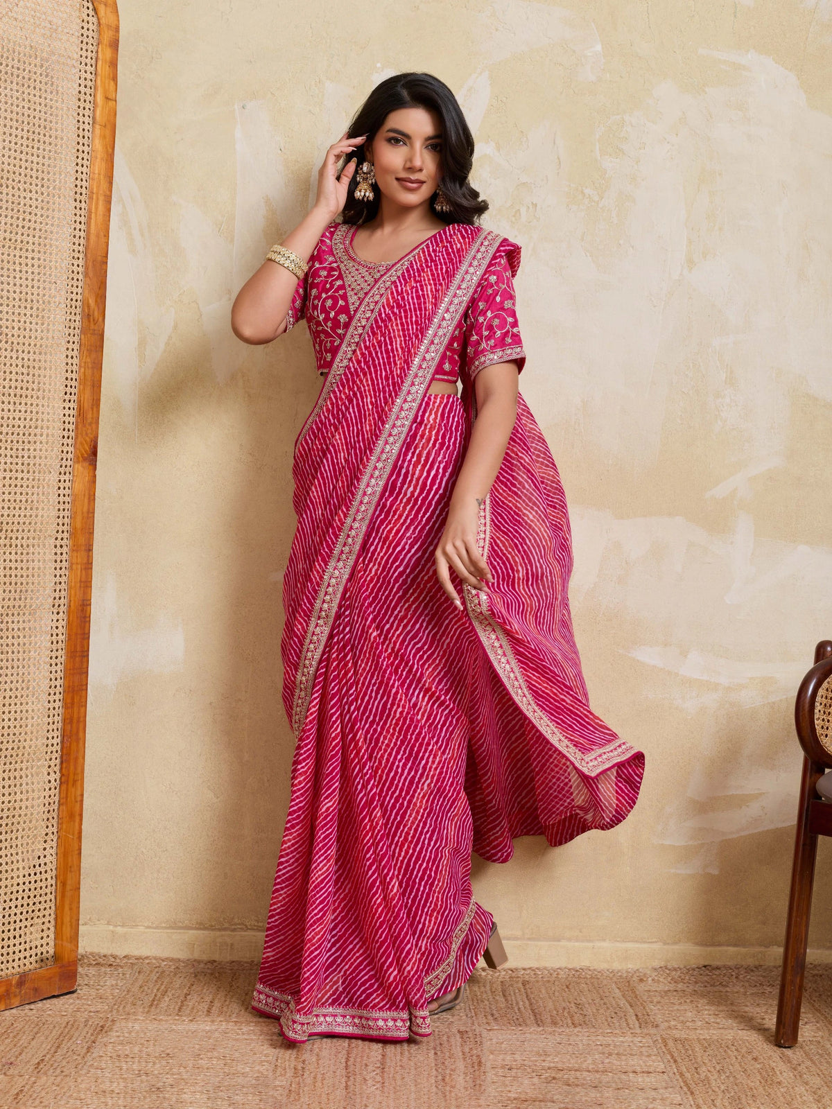 Woman wearing a pink saree with a beige wall background