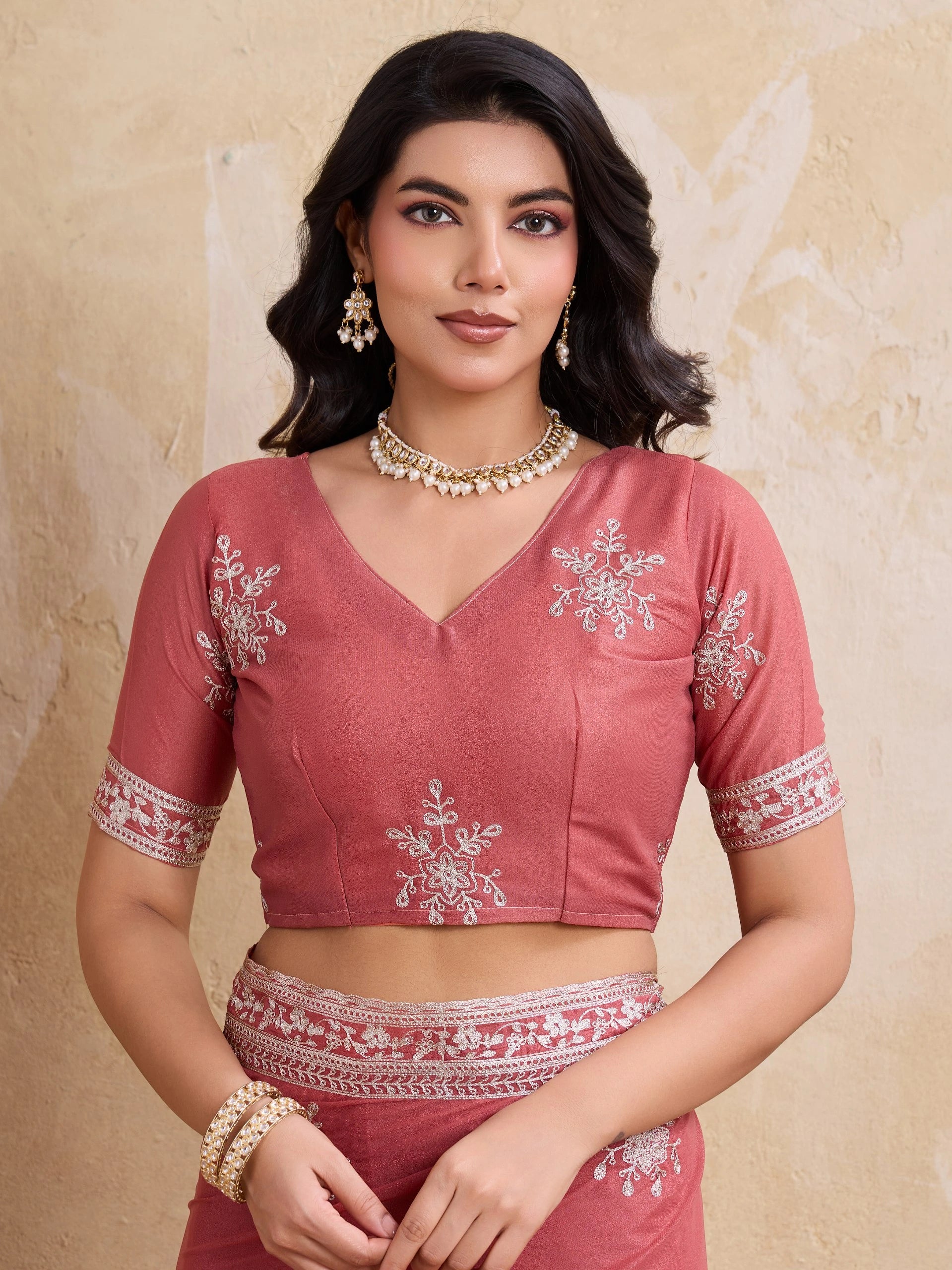 Woman wearing a pink traditional outfit with intricate designs on a beige background