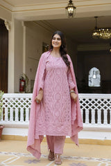 Woman in a pink traditional outfit standing in a decorated indoor setting.