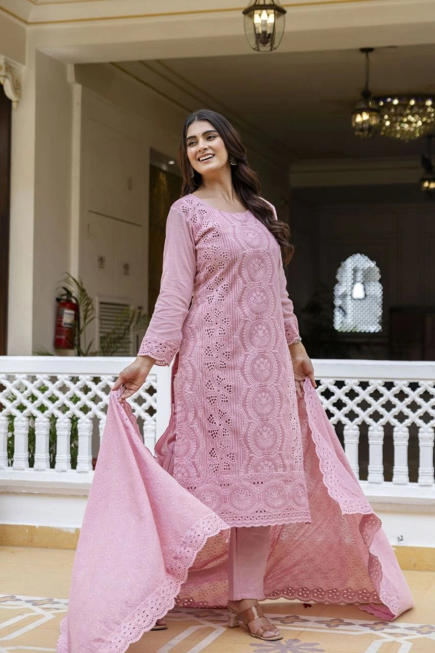 Woman in a pink traditional outfit standing in an elegant indoor setting.