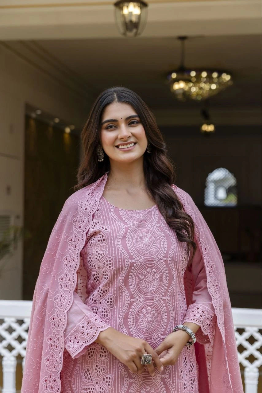 Woman in a pink traditional outfit with intricate patterns indoors.