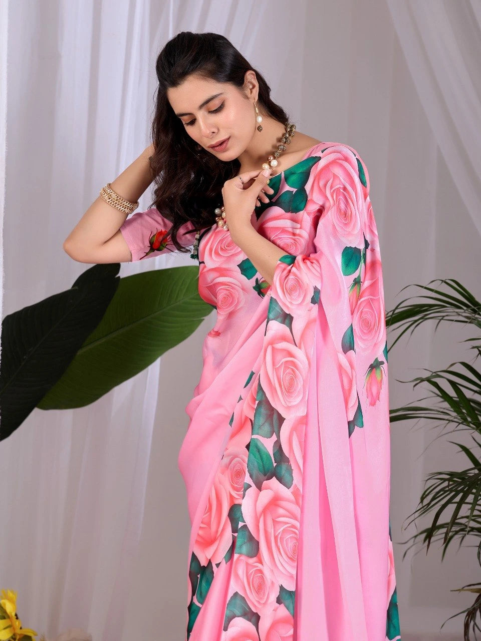 Woman wearing a pink saree with floral patterns against a white background