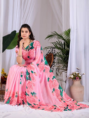 Woman in a pink floral saree sitting in a decorated room with plants and flowers.