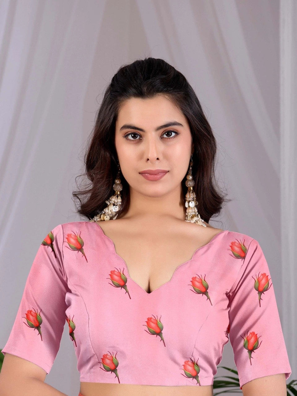 Woman wearing a pink blouse with floral patterns against a plain background