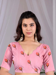 Woman wearing a pink blouse with floral patterns against a plain background