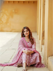 Woman in a pink traditional outfit sitting on a stone floor with a warm-toned wall in the background