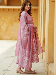 Woman wearing a pink traditional outfit with white patterns in an outdoor setting.