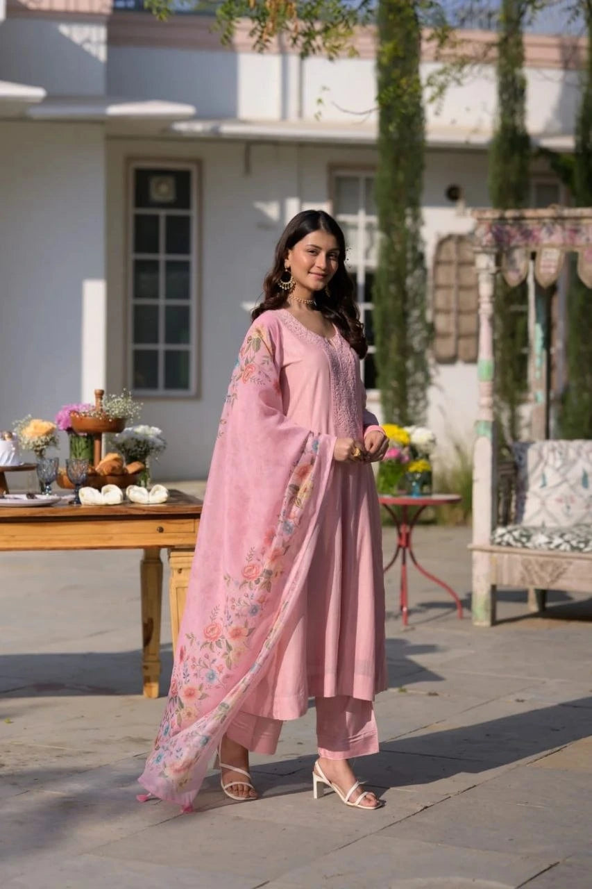 Woman in a pink traditional outfit standing outdoors with a garden background
