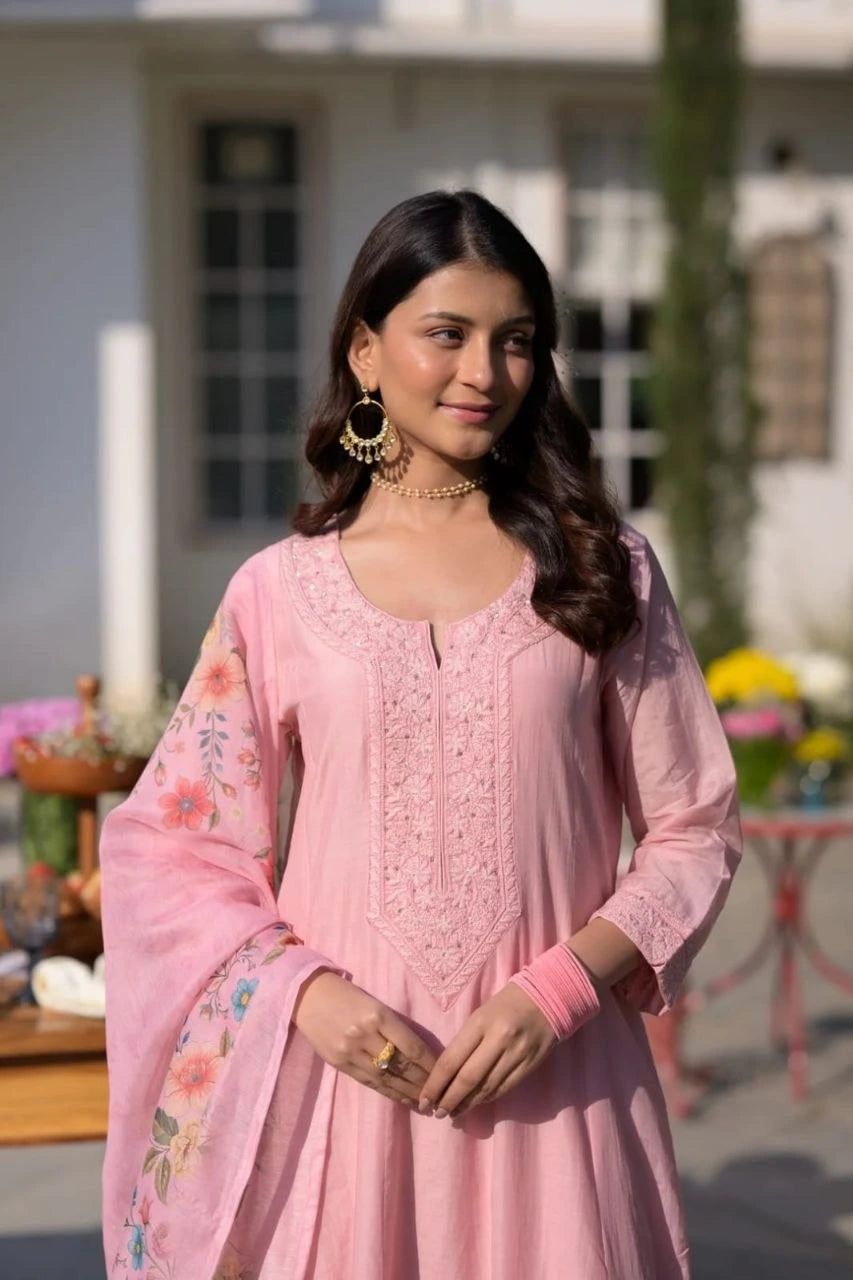 Woman wearing a pink traditional outfit with floral patterns outdoors.