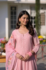 Woman wearing a pink traditional outfit with floral patterns outdoors.