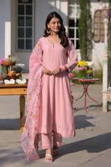 Woman in a pink traditional outfit standing outdoors with decorative elements.