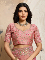 Woman wearing a pink embroidered traditional outfit with a neutral background