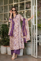 Woman in a floral dress with purple accents standing in a decorative indoor setting.