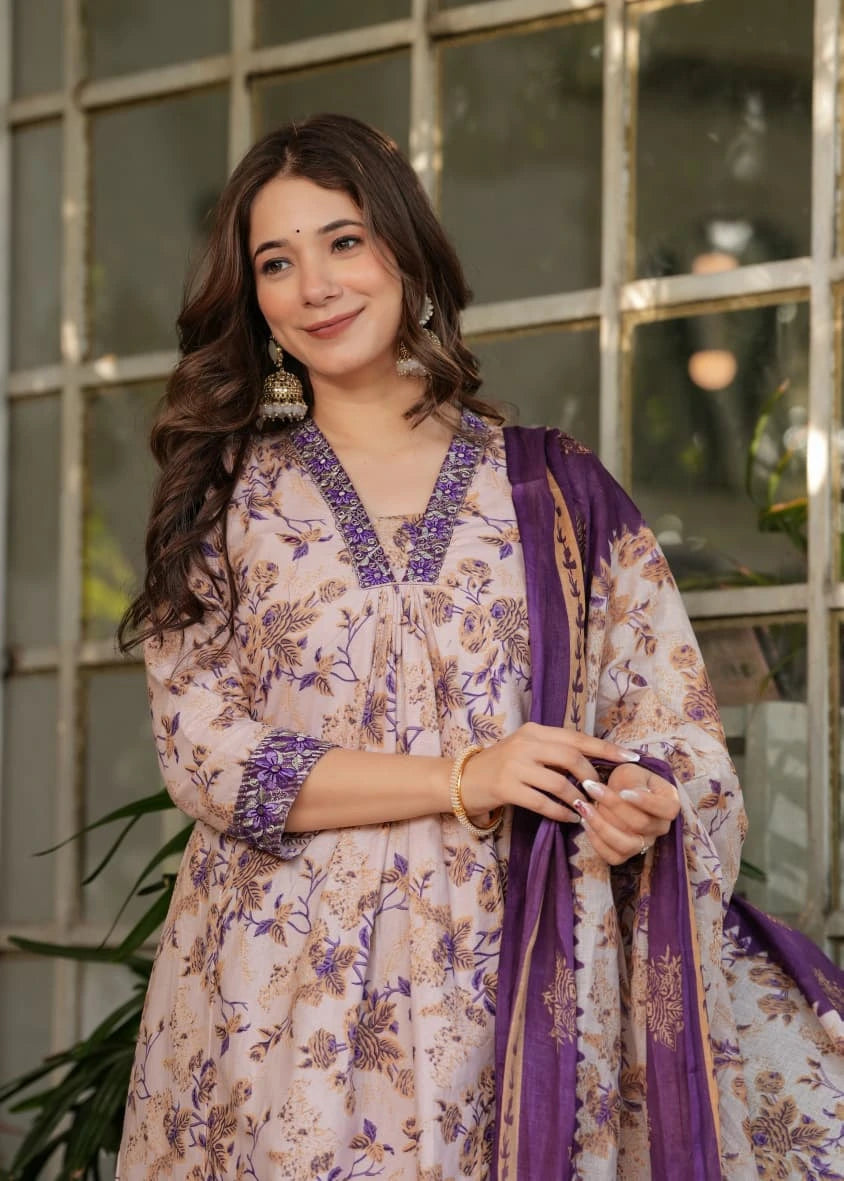 Woman wearing a floral dress with purple accents in front of a glass window.