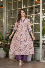 Woman wearing a floral dress with a purple top and pants in an indoor setting with plants.