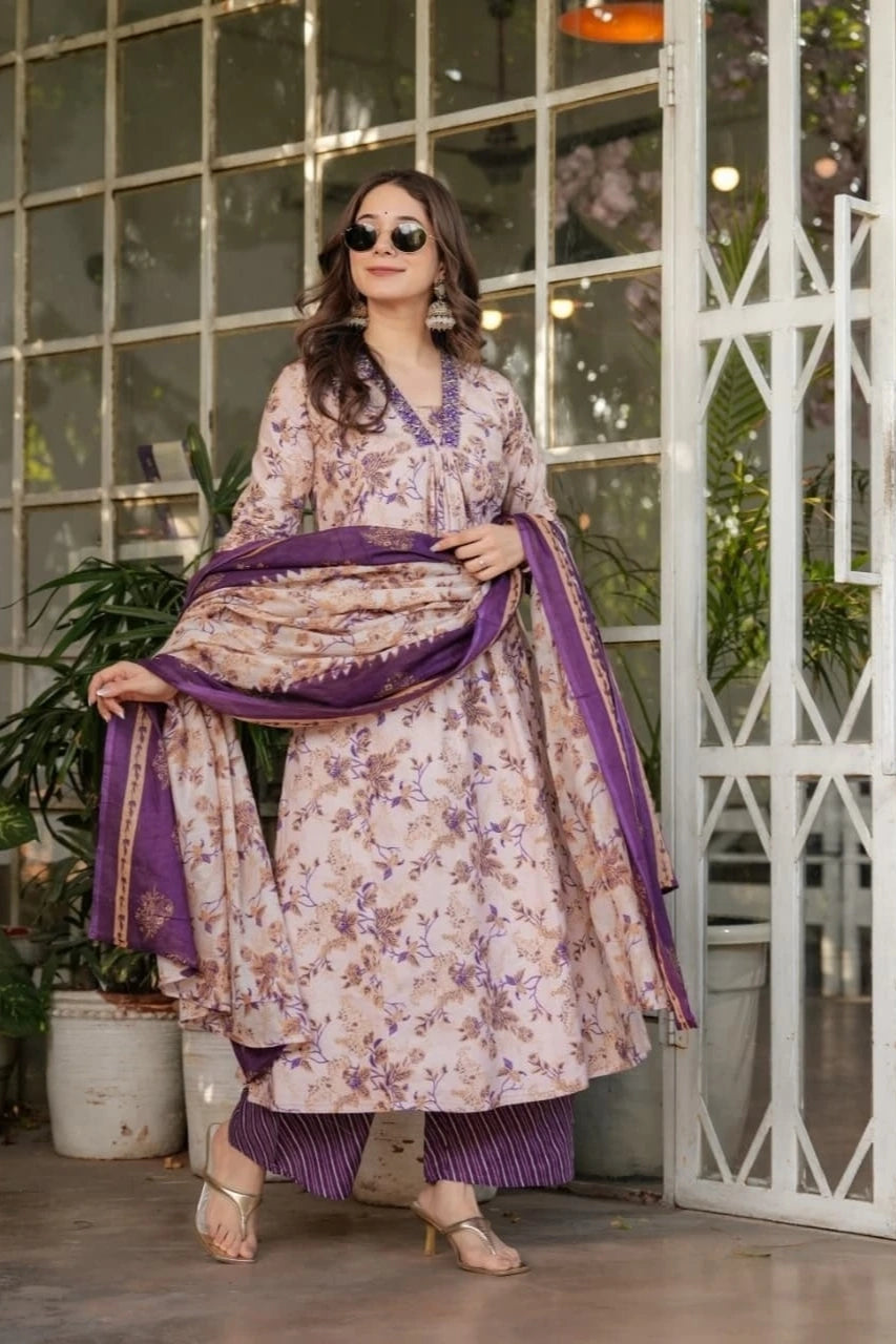 Woman in a floral dress with purple accents standing indoors.
