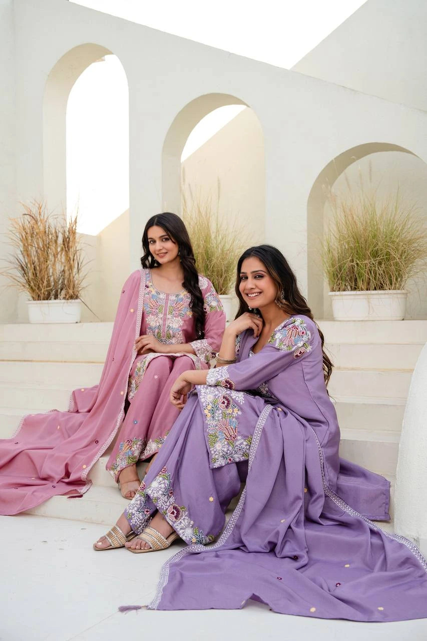 Two women in traditional outfits sitting on a white staircase with a neutral background
