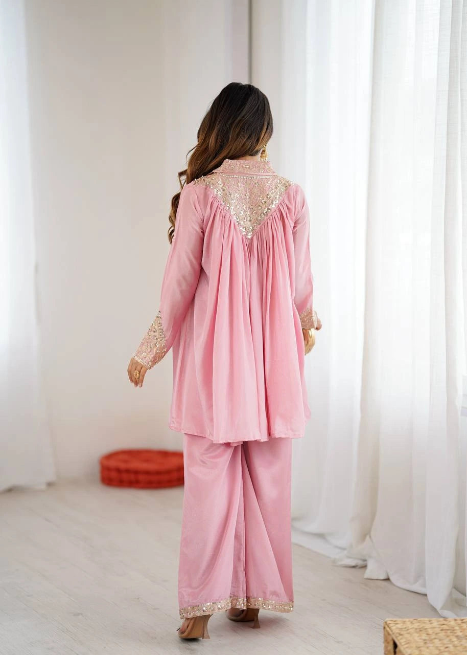 Woman wearing a pink traditional outfit with lace details in a minimalistic setting.