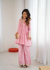 Woman in a pink traditional outfit standing in a room with white curtains.